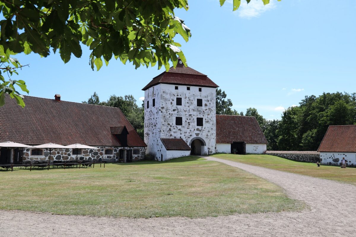 Hovdala Castle from the front on a summerday with benches and parasols on the left side