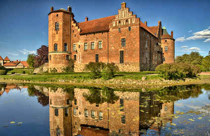 Torup Castle with the lake in front on a sunny day with blue sky